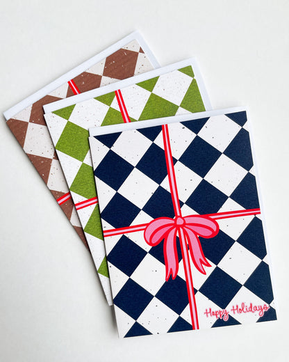 Three festive greeting cards with checkered patterns and red ribbons on a white background.