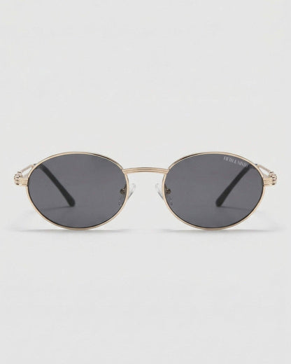 Gold-framed sunglasses with dark lenses on a light gray background