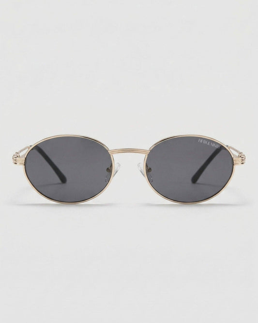 Gold-framed sunglasses with dark lenses on a light gray background