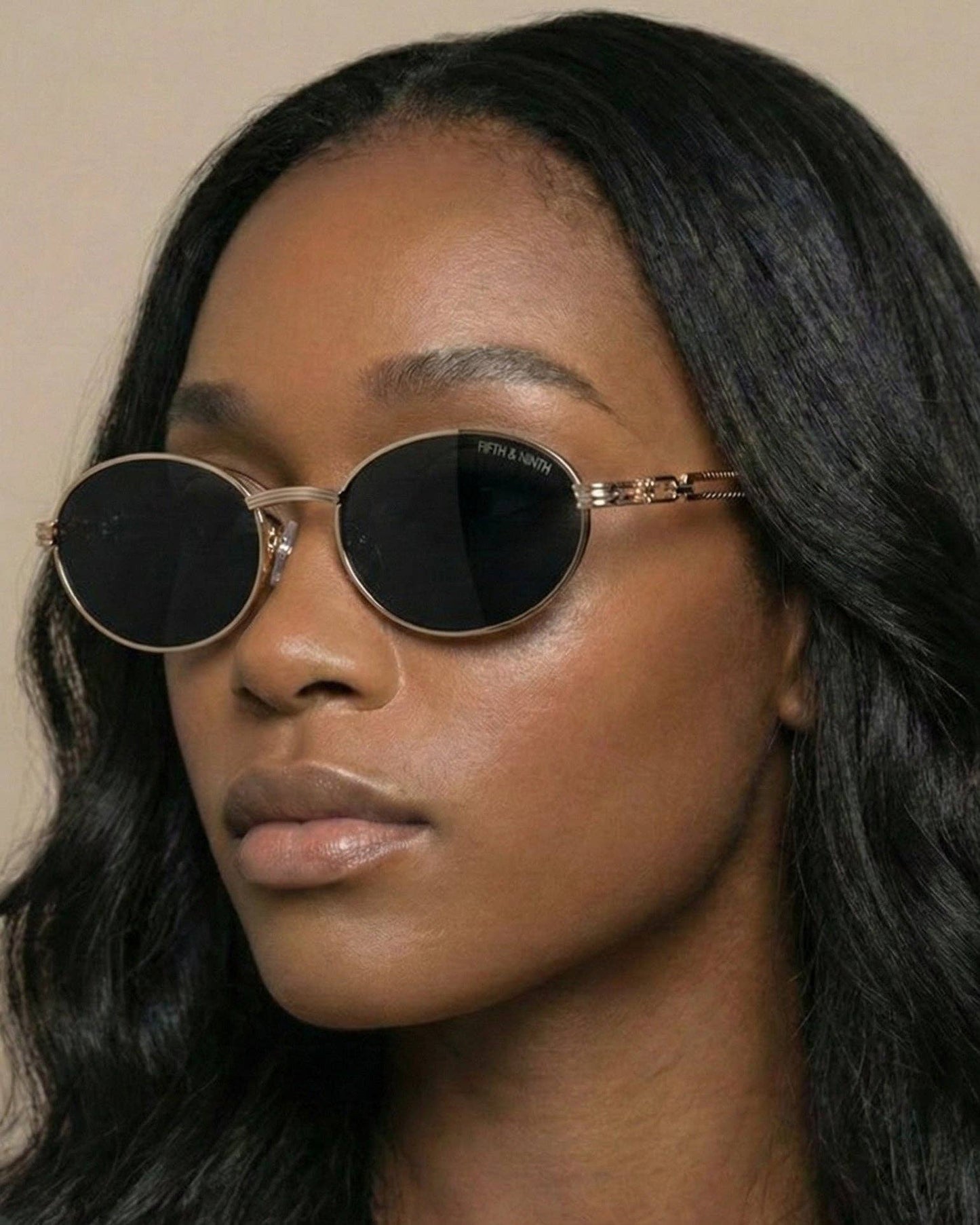 Woman wearing round sunglasses with a neutral background