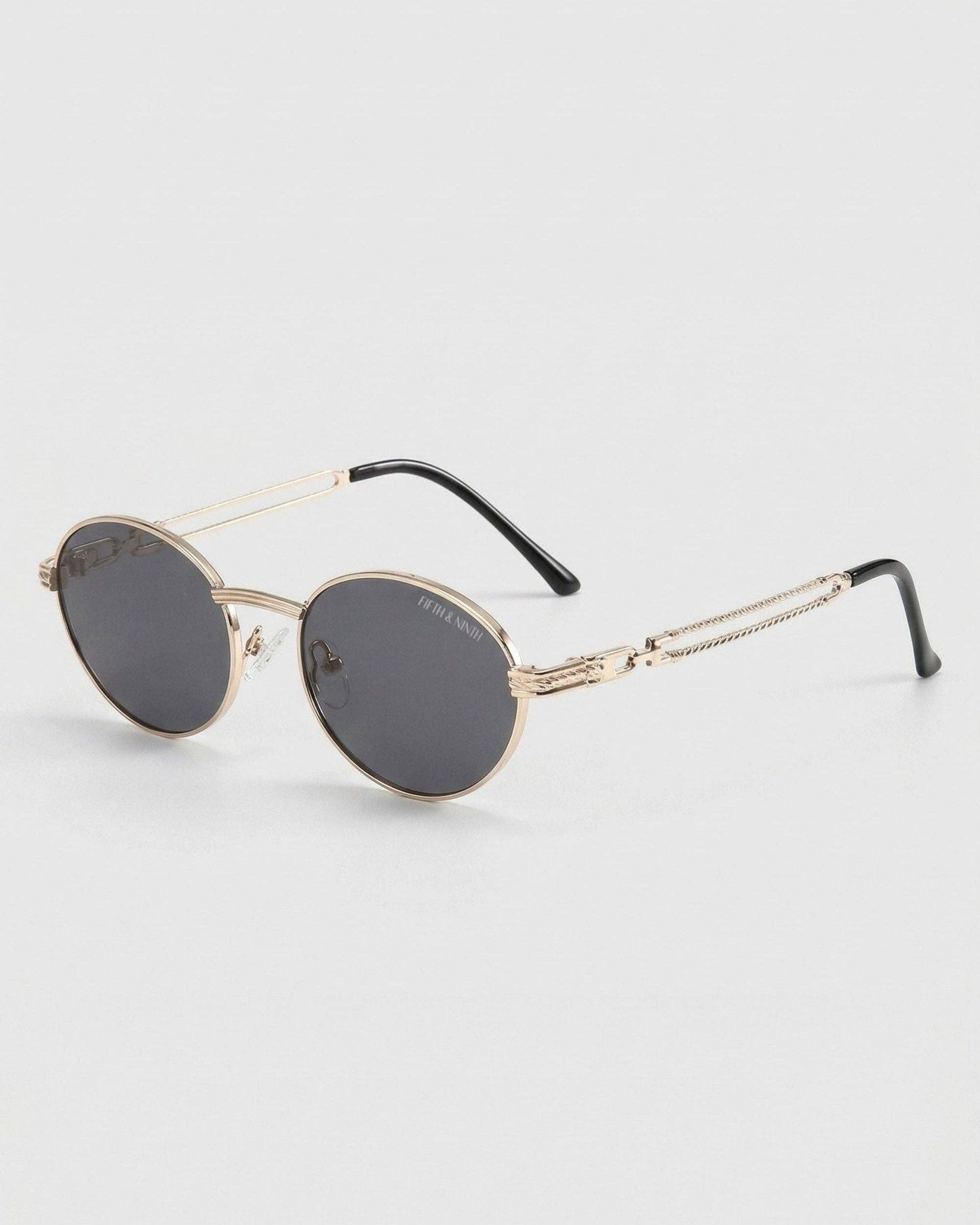 Round sunglasses with gold frame and black lenses on a light gray background