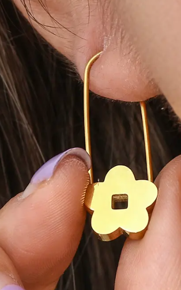 Gold earring with a floral design worn by a person
