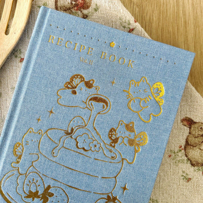 Blue recipe book with gold illustrations on a wooden surface, Blue Linen Recipe Book