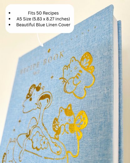 Blue linen recipe book with gold illustrations on a beige background