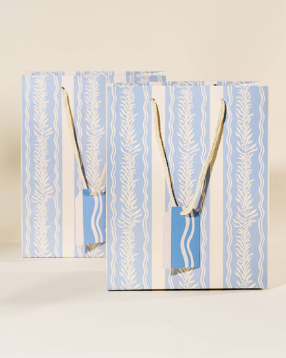 Two blue gift bags with white patterns and handles on a beige background, Blue Vine Medium Paper Gift Bag
