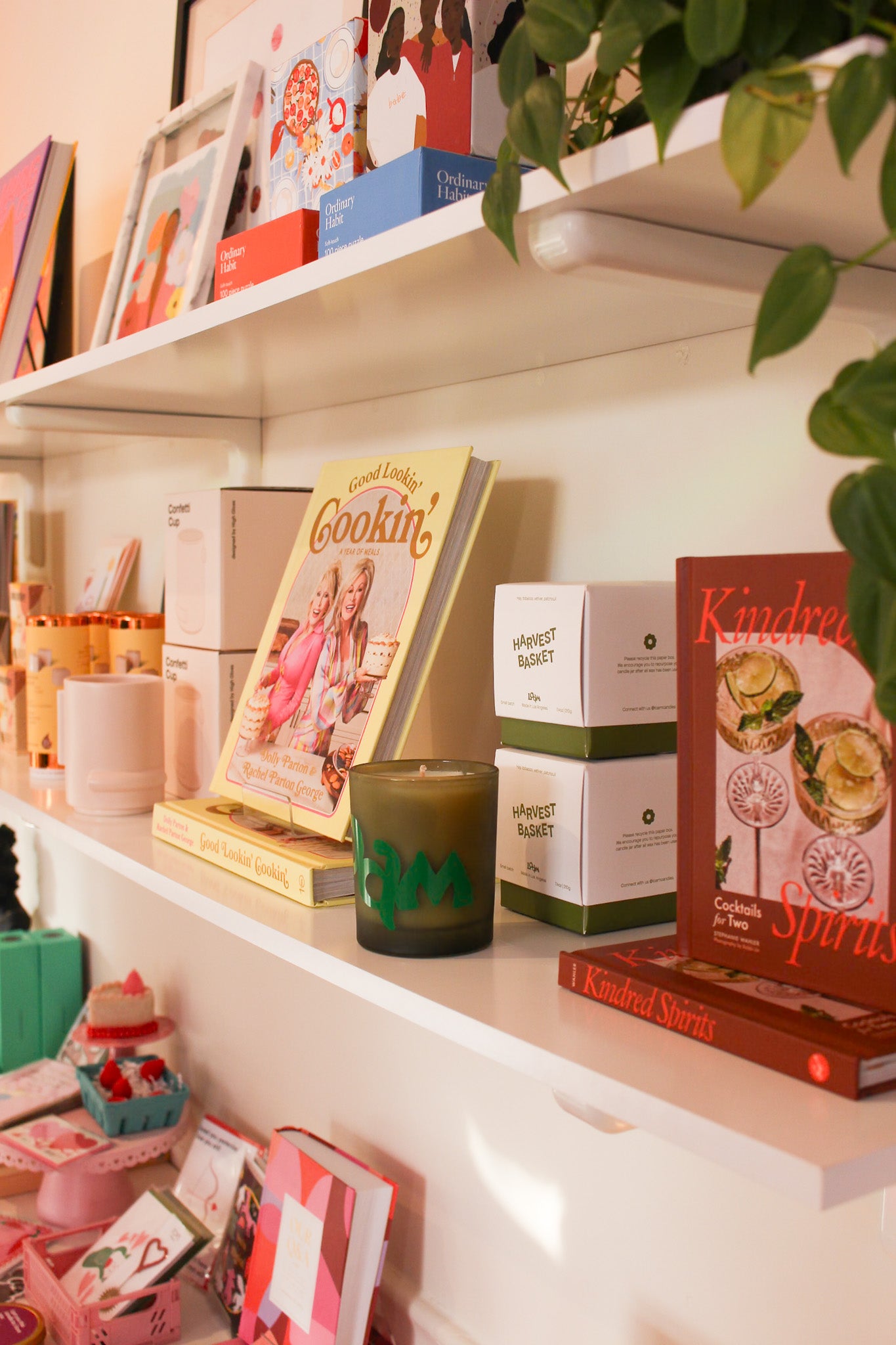 Shelf with cookbooks, a candle, and decorative items on a white surface.
