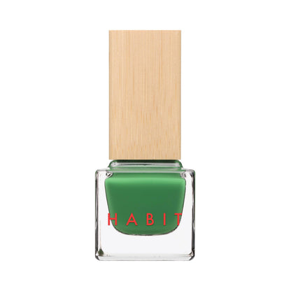 A bottle of green nail polish with a light wood-grain textured cap, featuring the brand name 'HABIT' in red text on the clear glass bottle, set against a plain white background.