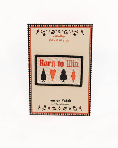 Patch with 'Born to Win' text and card suit symbols on a beige background