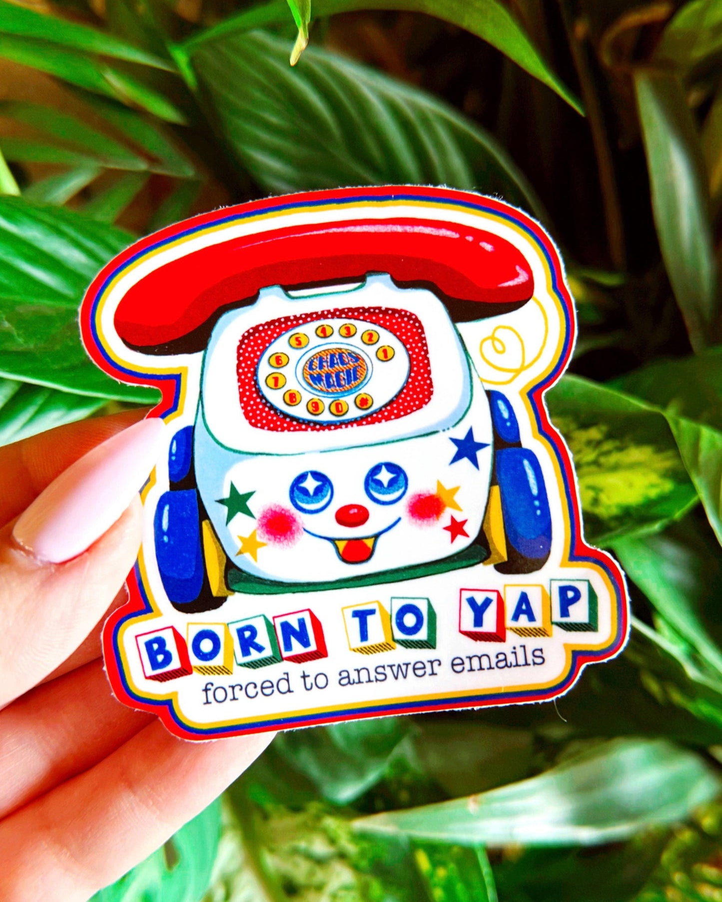 Colorful sticker of a cartoon telephone with text 'Born to Yap, forced to answer emails' held against a green leafy background.
