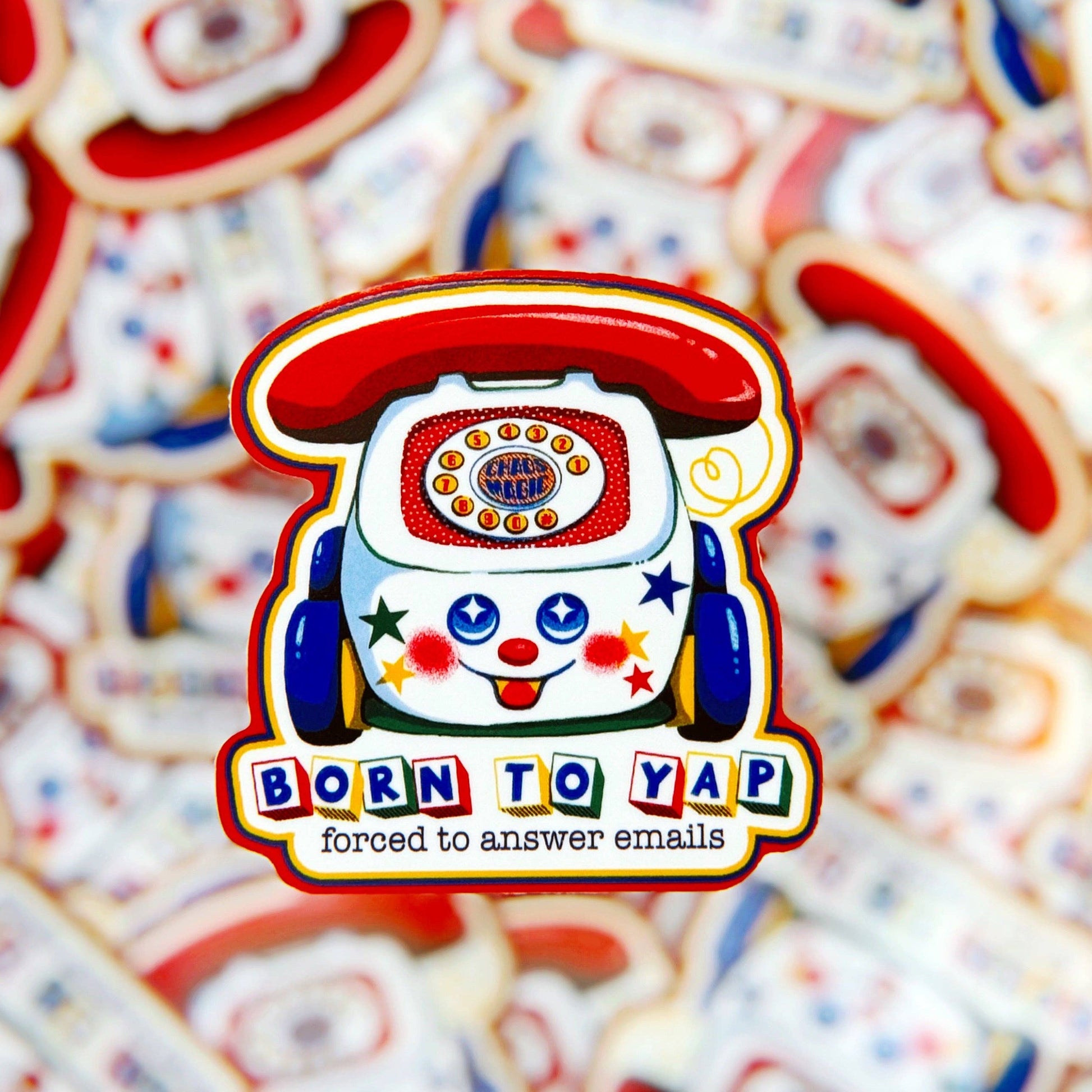 Colorful phone-shaped sticker with a smiling face and text 'Born to Yap, forced to answer emails' on a background of similar stickers.
