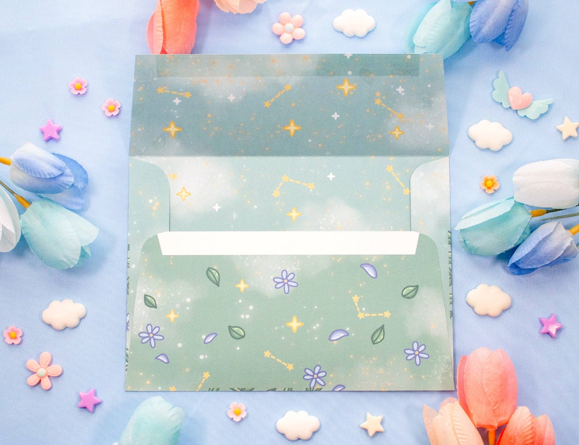 Two green envelopes with star and flower patterns on a blue background with decorative flowers.