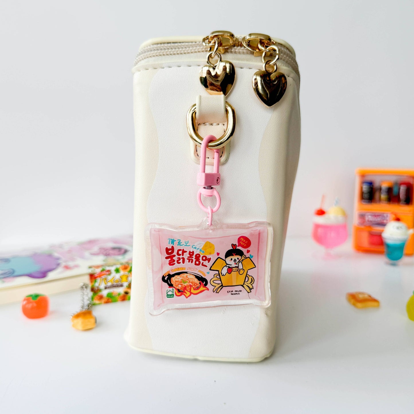 White pouch with gold heart-shaped charms and a cartoon character badge holder on a white background.