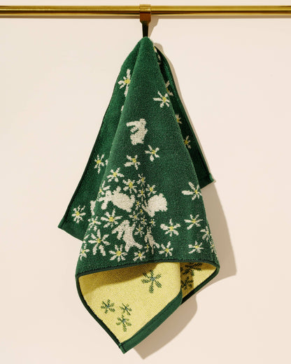 Green towel with white floral pattern hanging on a gold rod against a beige background