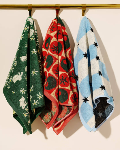 Three patterned towels hanging on a rack against a beige background