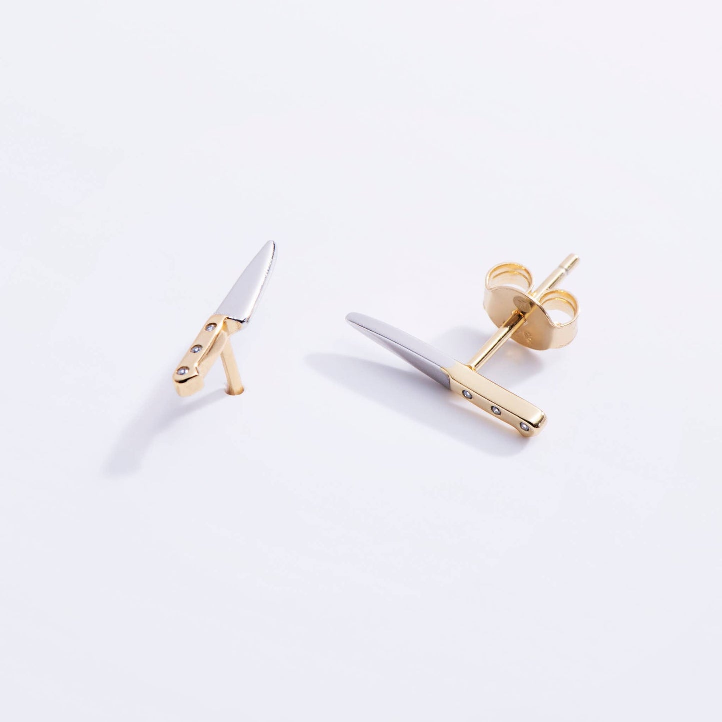 Gold and silver earrings on a white background