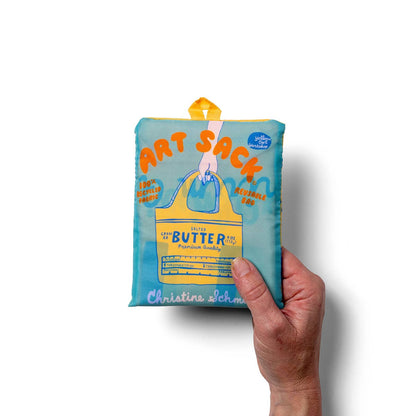 Hand holding a blue 'Art Sack' product with branding on a white background