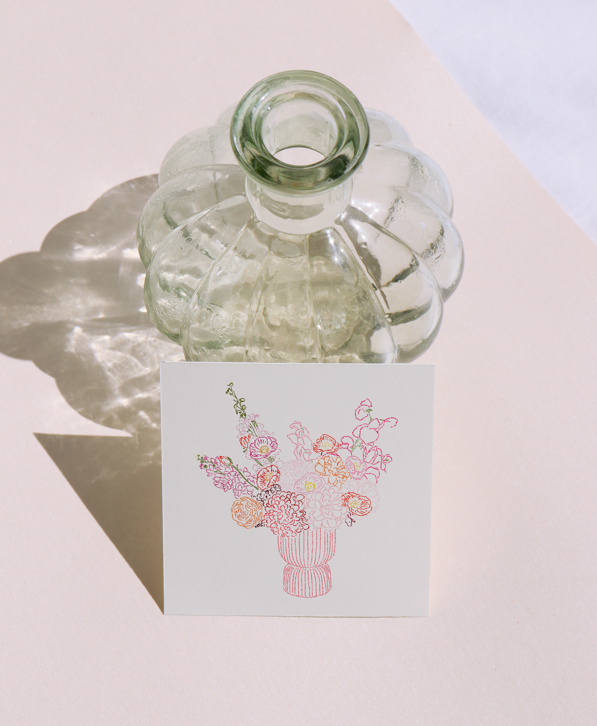 Clear glass bottle with a decorative card featuring a floral design on a light background
