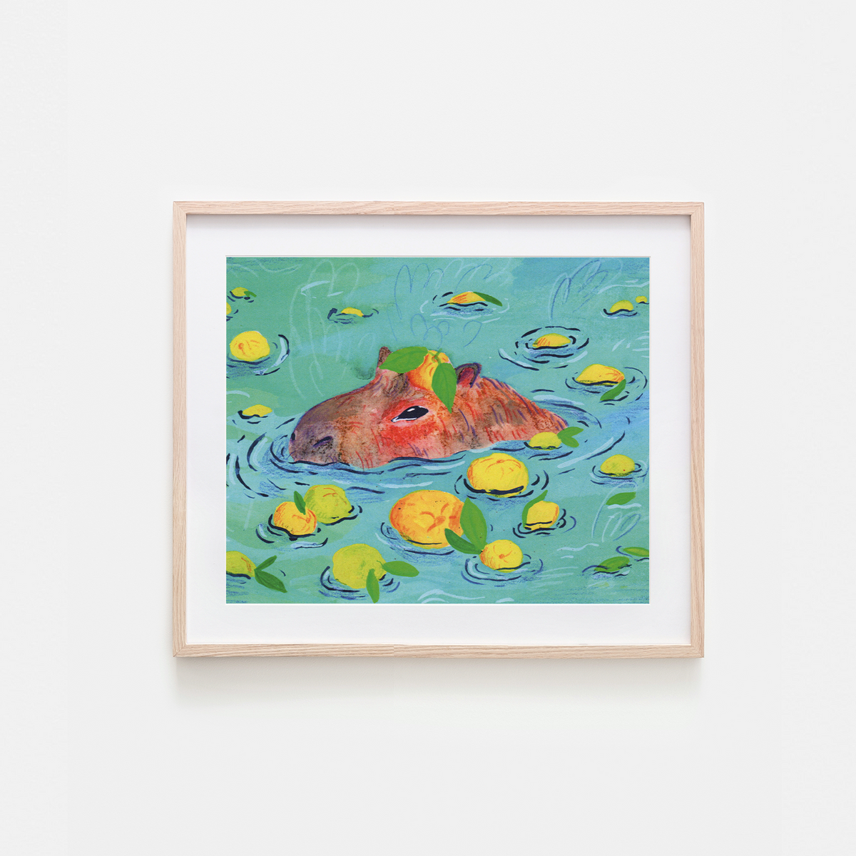 A framed art print featuring a whimsical illustration of a capybara swimming in turquoise water with yellow lemons and green leaves, set against a clean white background.