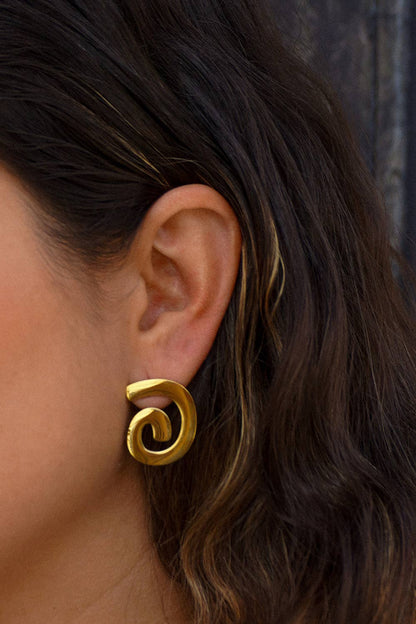 Gold spiral earring worn by a person with dark hair.