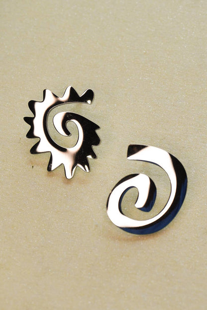 Two silver spiral earrings on a beige background