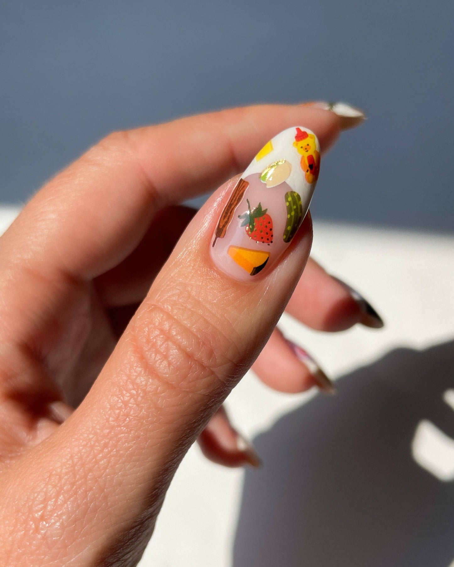 Nail with colorful design featuring fruits and vegetables on a neutral background, Charcuterie Nail Art Stickers