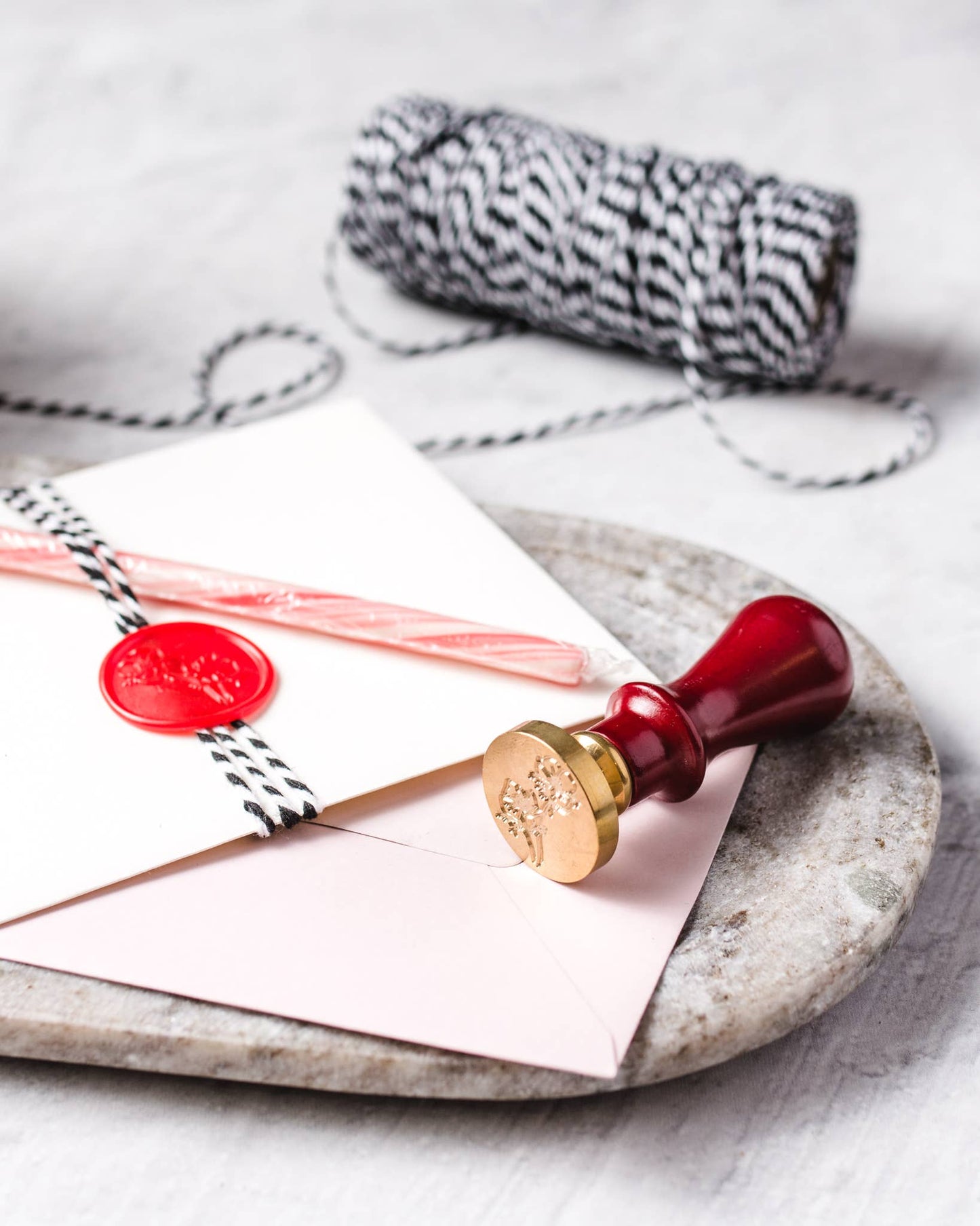Red wax seal on a letter with a marble surface and yarn in the background