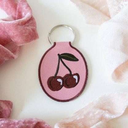 Keychain with cherry design on a soft pink fabric background