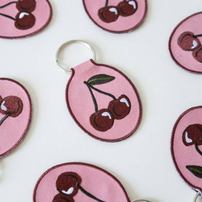 Cherry-themed keychains on a white background