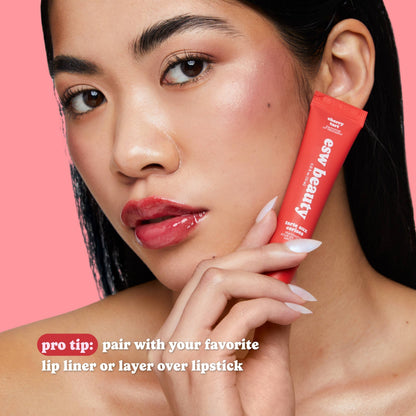 Woman holding a red makeup stick with 'ew beauty' branding against a pink background