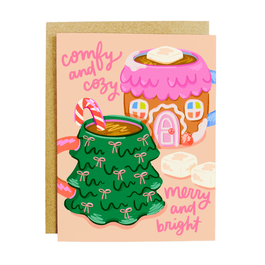 Greeting card with Christmas-themed illustrations of a green mug, pink gingerbread house, and candy canes on a peach background.