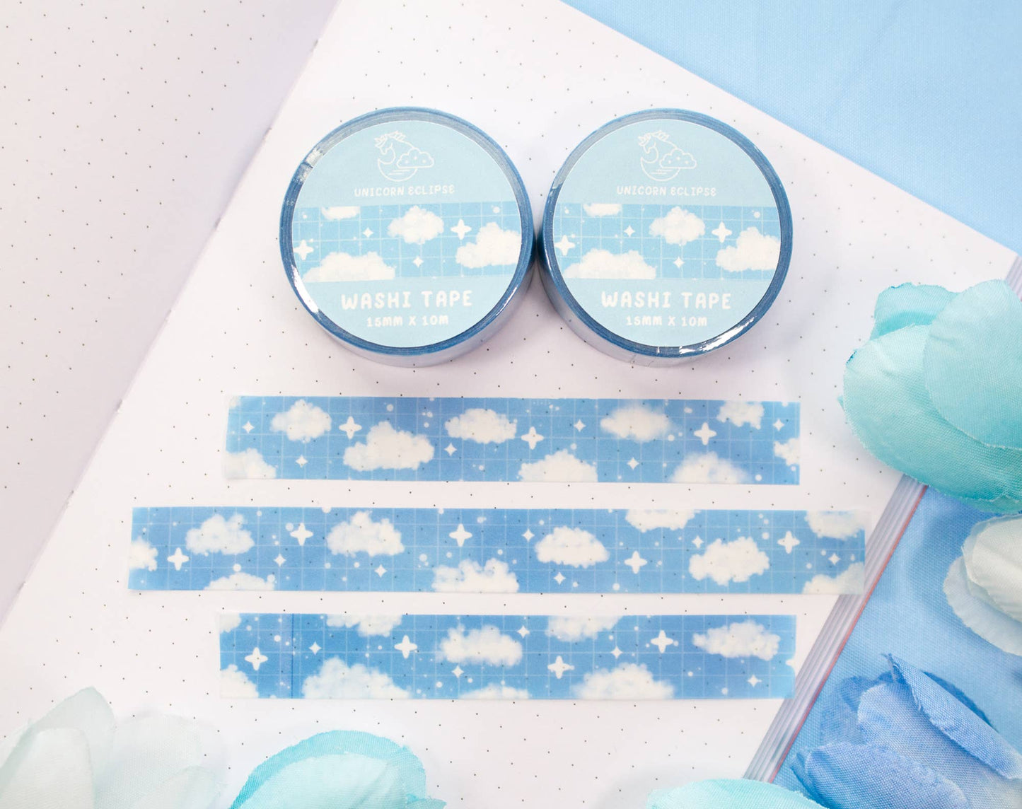 Two rolls of cloud-themed washi tape on a notebook with some tape already applied.
