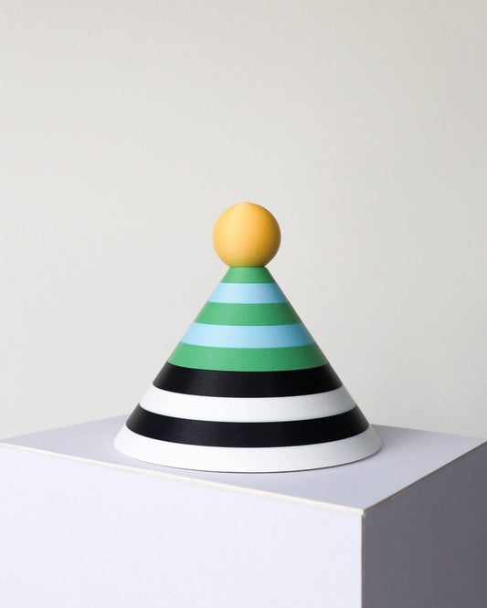 A cone-shaped dish with horizontal stripes in yellow, green, light blue, black, and white, topped with a round yellow handle, displayed on a white pedestal against a light gray background.