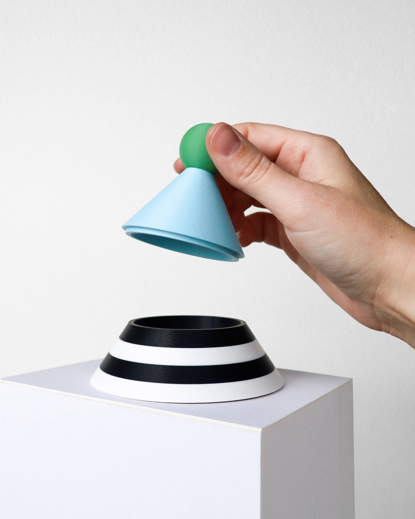 Hand holding a colorful cylindrical object on a white background