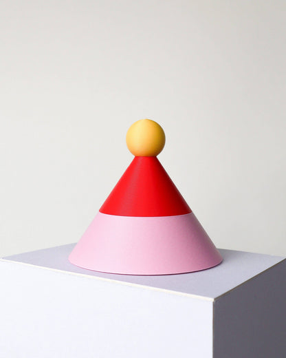 Colorful geometric object with a yellow sphere on top, red cone, and pink base on a white background