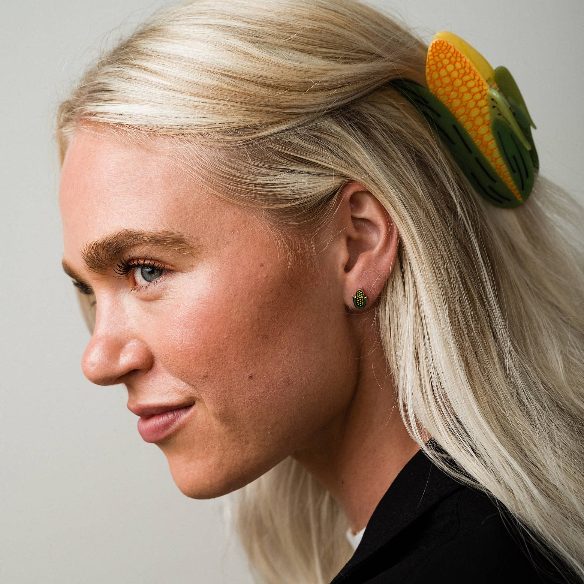 Person with corn-shaped hair clip on a plain background