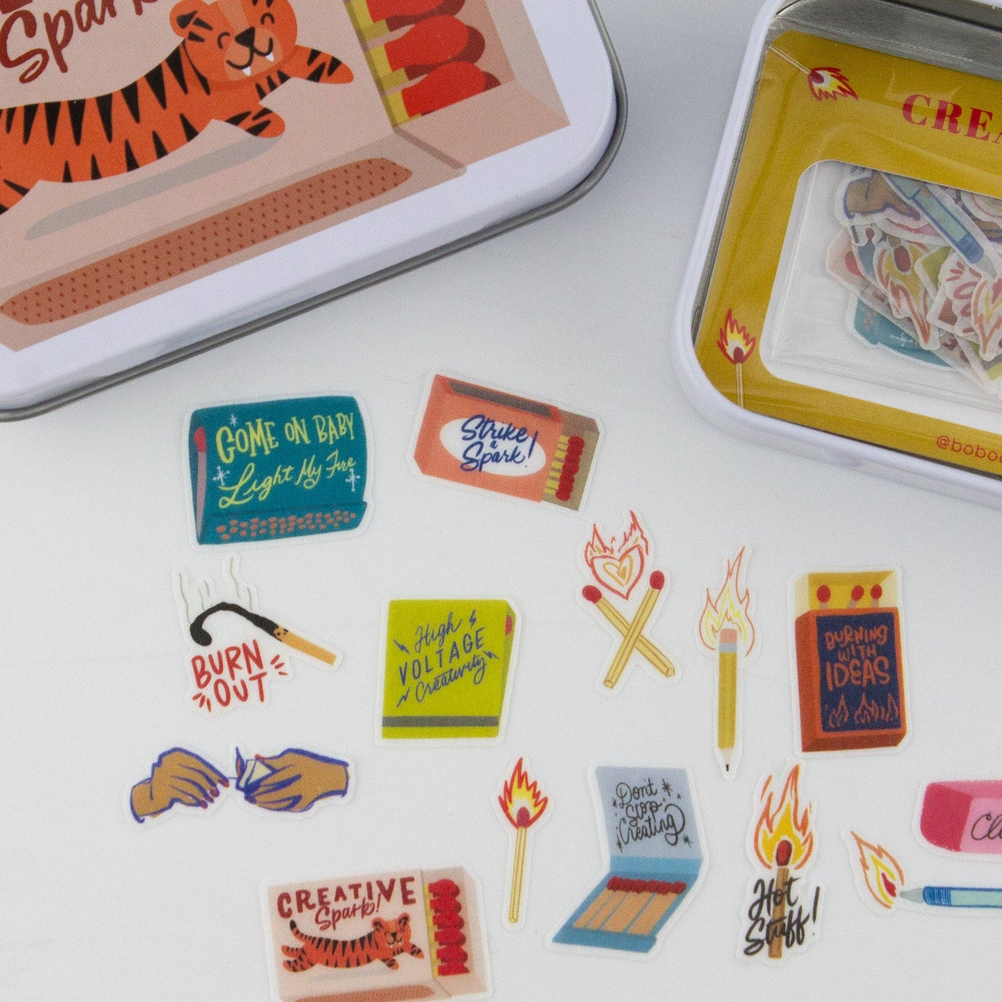 Colorful matchbox art and stickers on a white surface