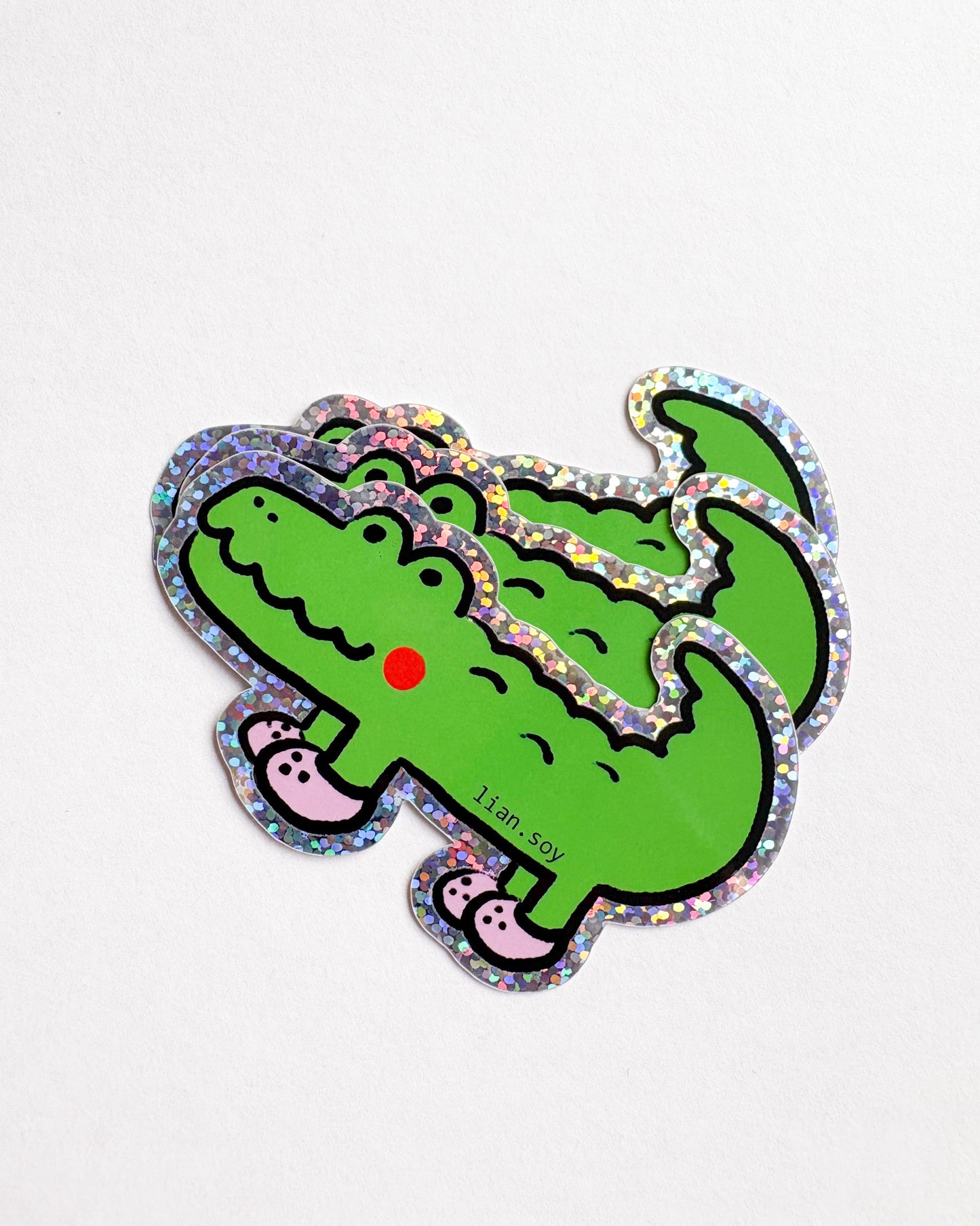 Green dinosaur-shaped sticker with colorful border on a white background