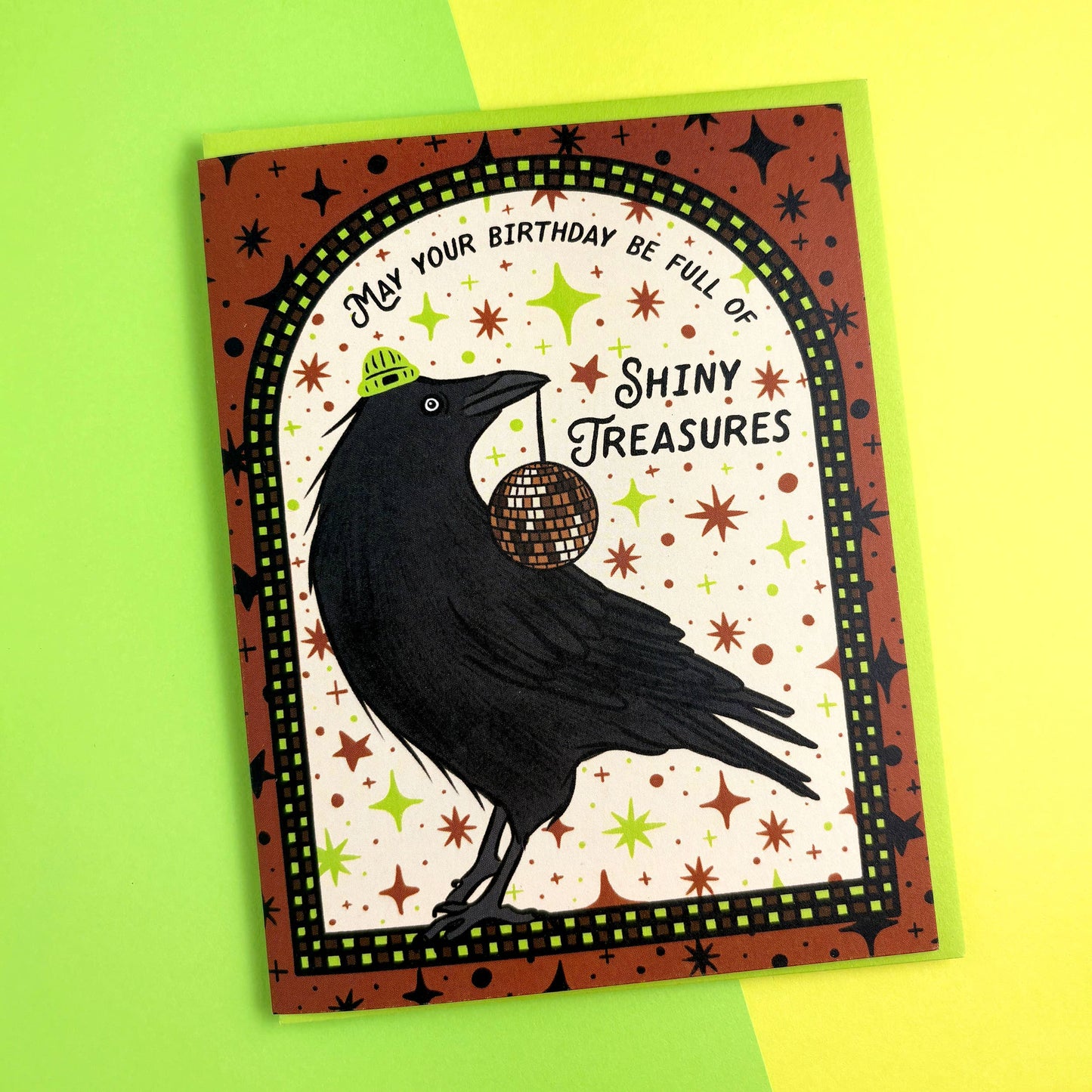 Greeting card with a black crow holding a disco ball on a green and yellow background