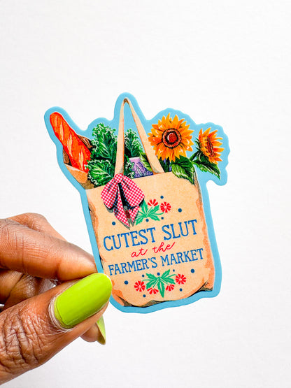 Sticker of a farmer's market bag with text held by a hand against a white background