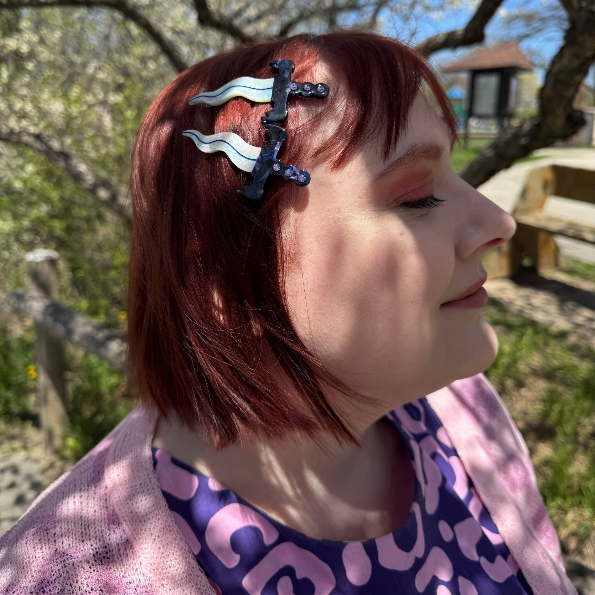 Person with a dagger hair clip set outdoors in a park-like setting