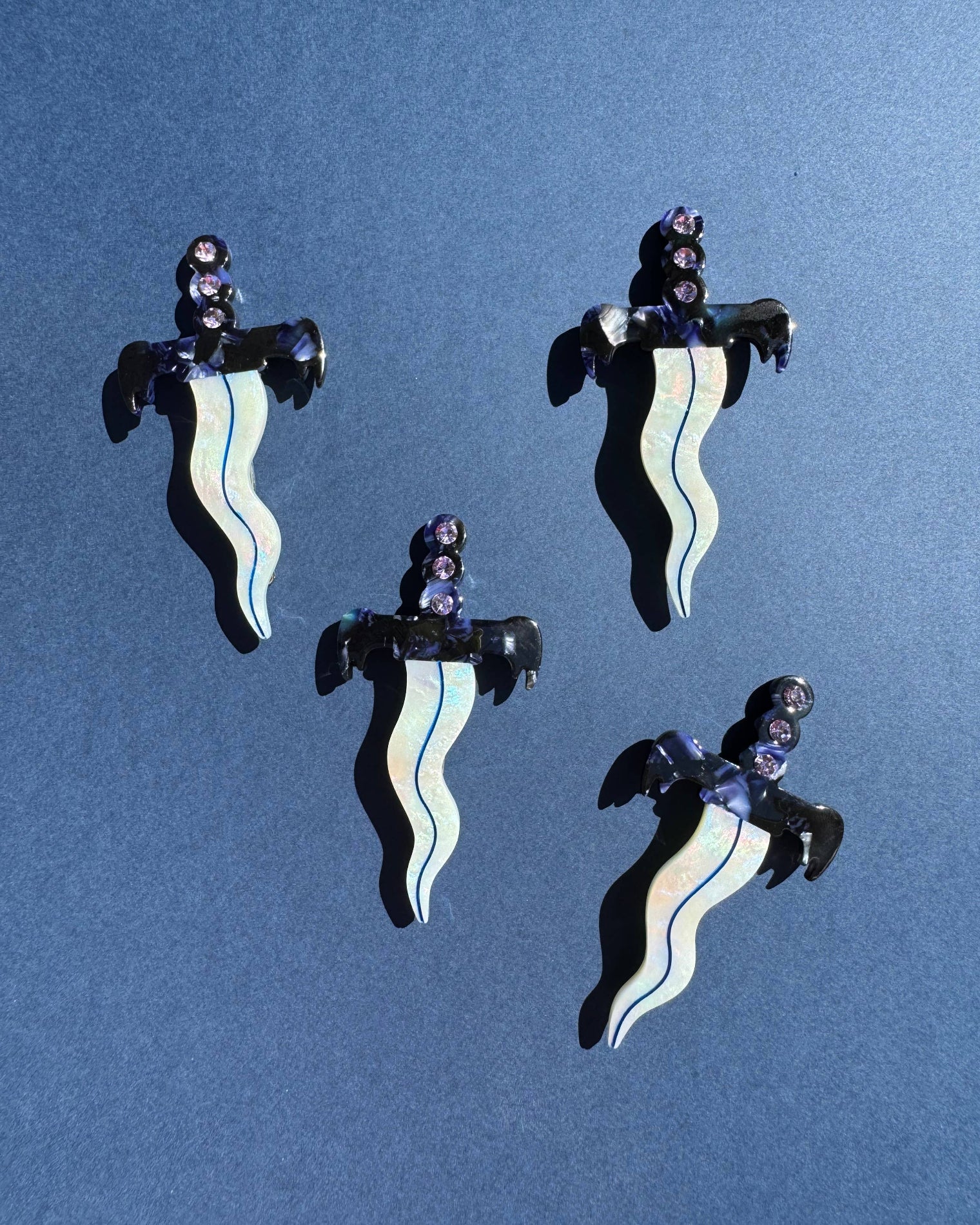 Four black and white striped earrings on a blue background