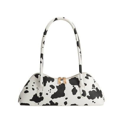 White handbag with black cow print pattern on a white background