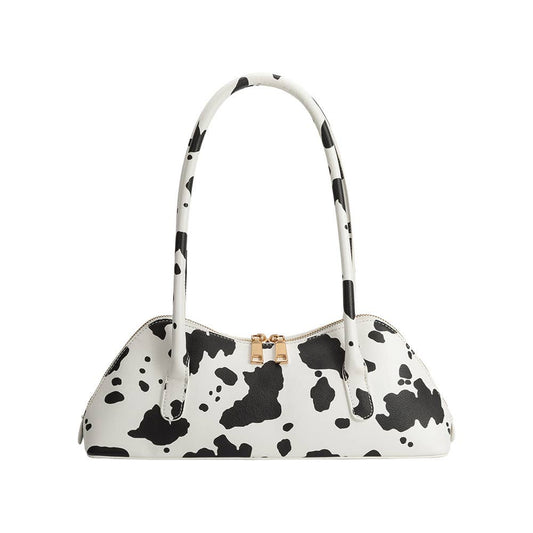 White handbag with black cow print pattern on a white background