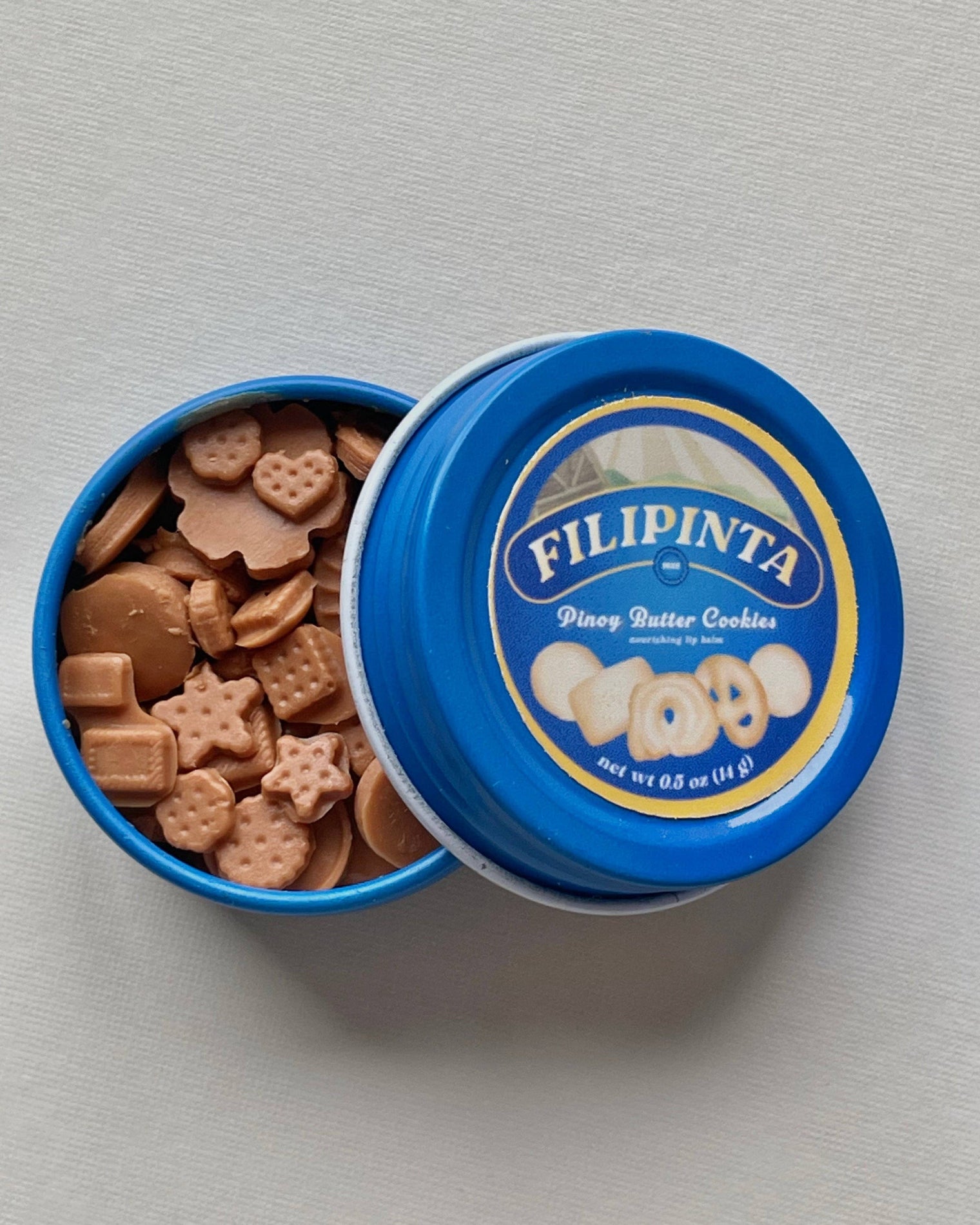 Open blue tin of Filipinta pine nut butter cookies on a gray background, Danish Butter Cookies inspired Lip Balm