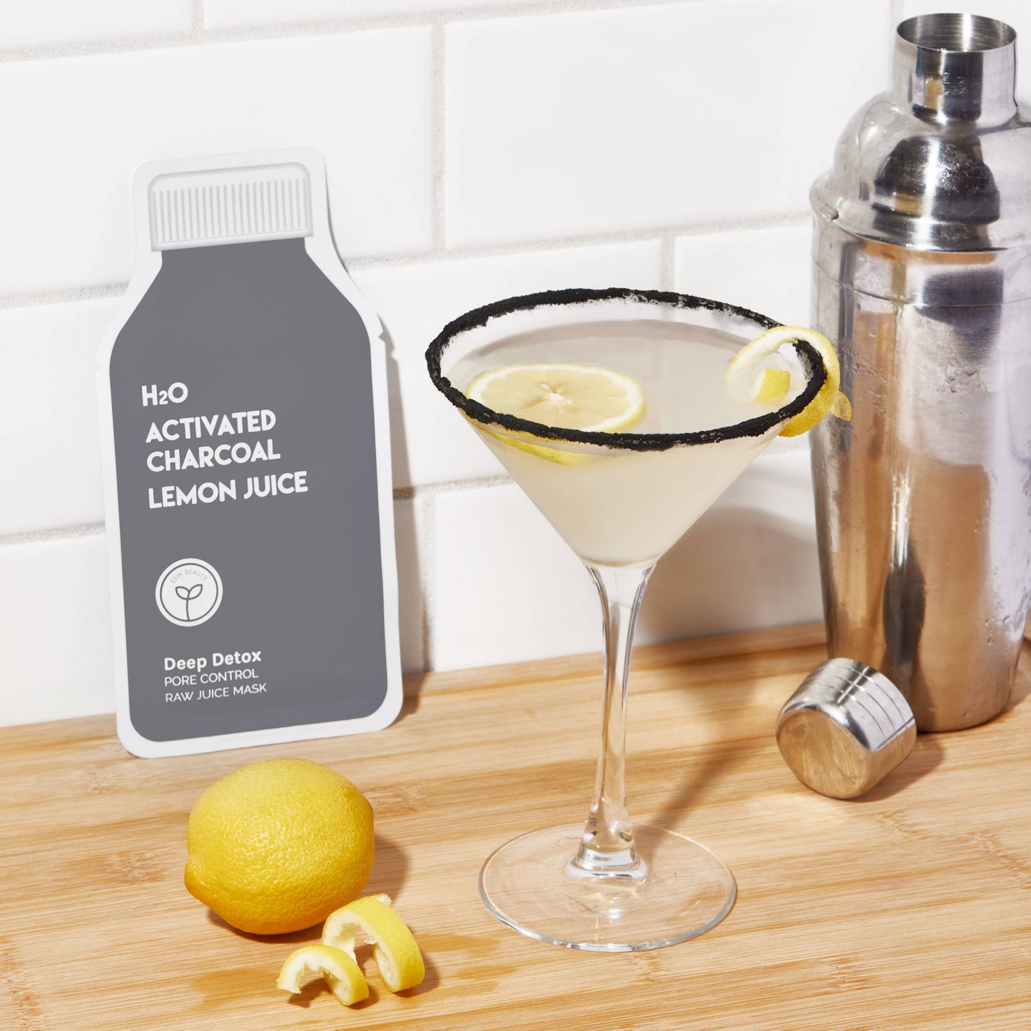 H2O Activated Charcoal Lemon Juice packaging with a cocktail and lemon on a wooden surface. Deep Detox Pore Control Raw Juice Sheet Mask
