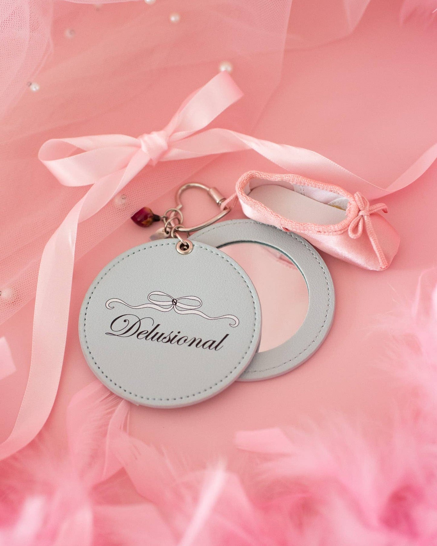 Round keychain with 'Delisional' branding on a pink background