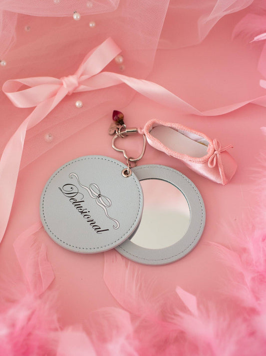 Round mirror with decorative keychain on a pink fabric background Delusional Mirror Keychain
