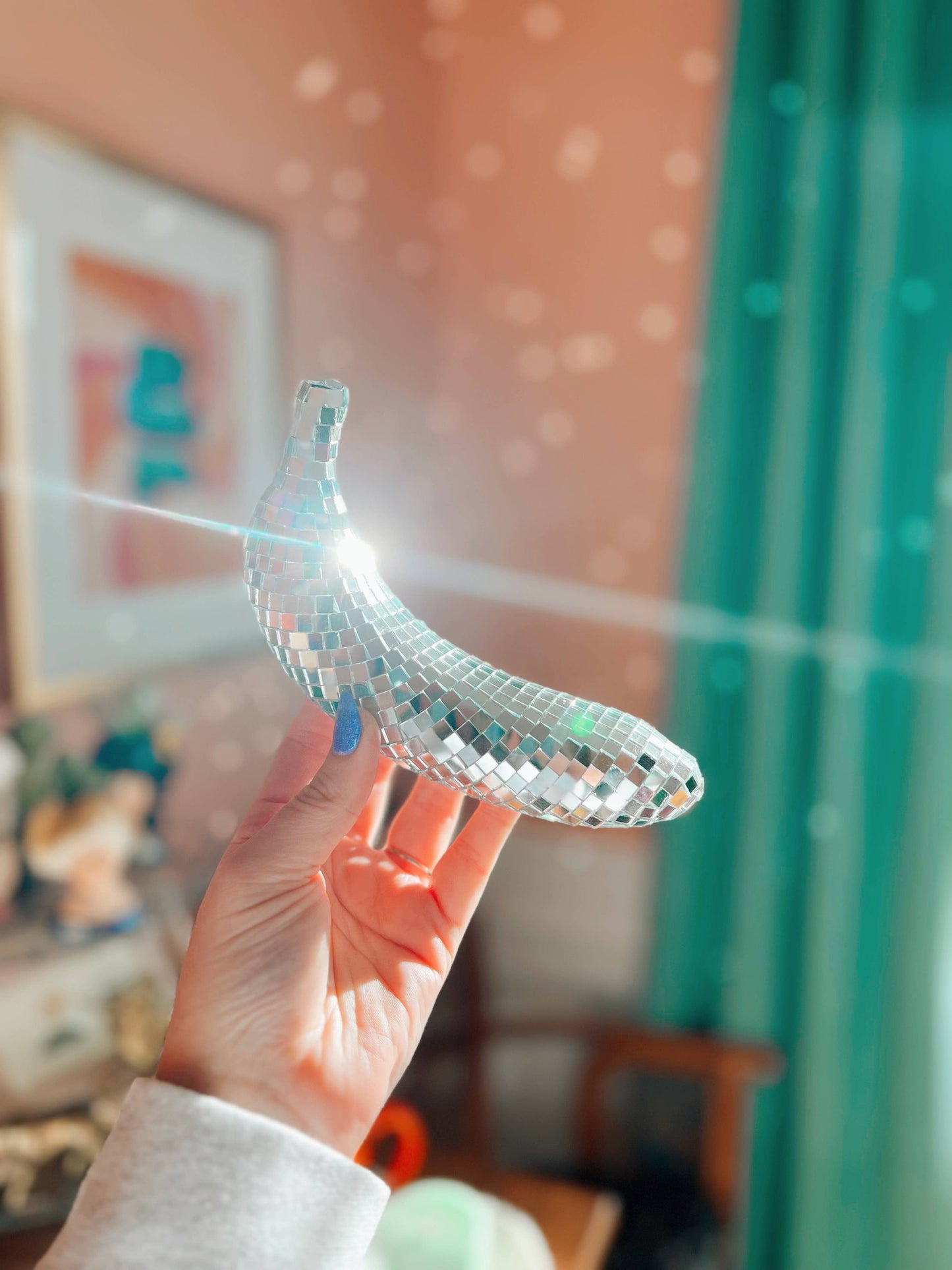 Hand holding a clear plastic object with a glittery finish against a blurred indoor background