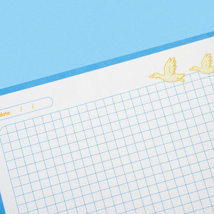 Grid paper with decorative corner stickers on a blue background