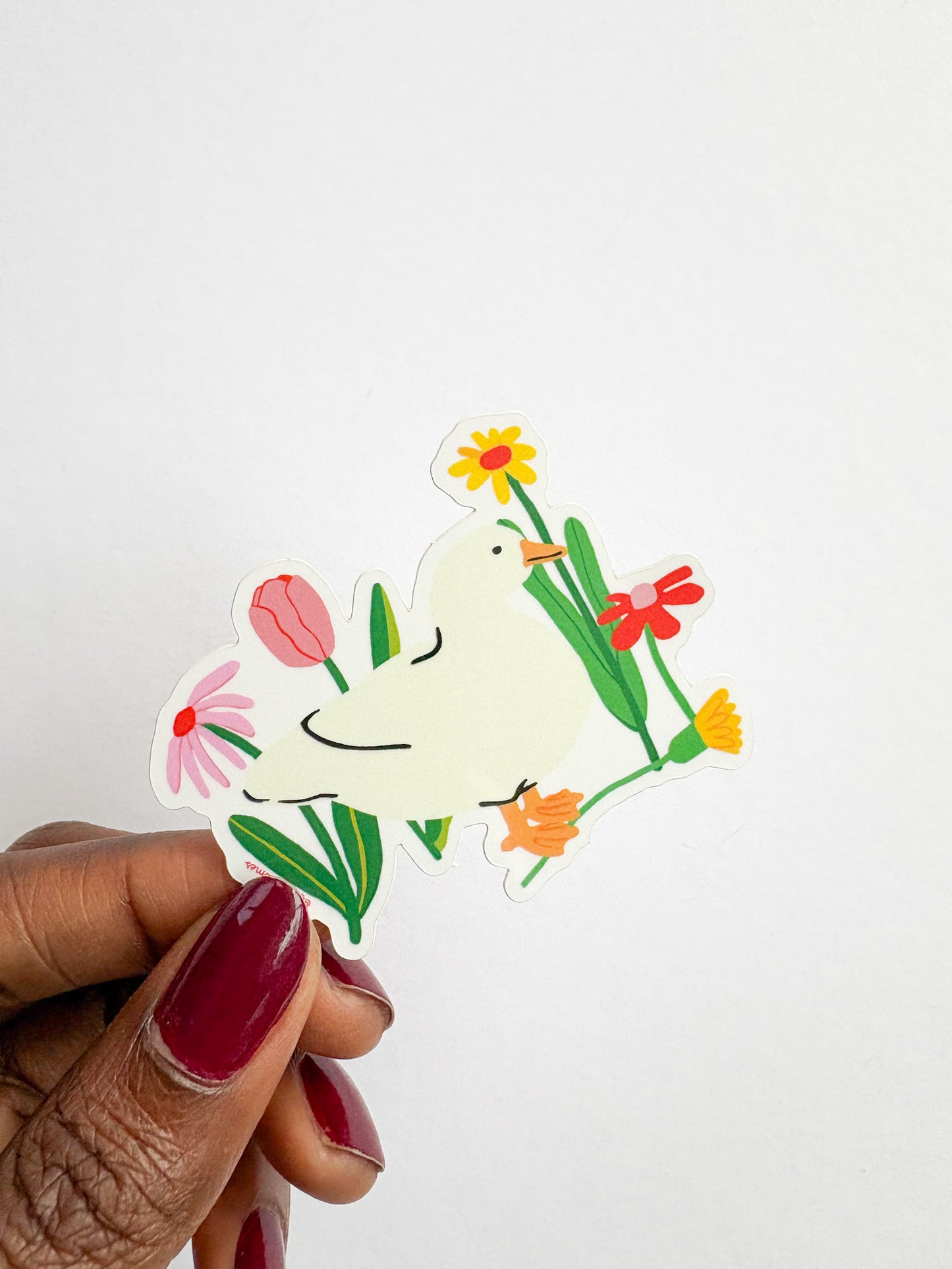 Hand holding a sticker of a dove with flowers on a white background